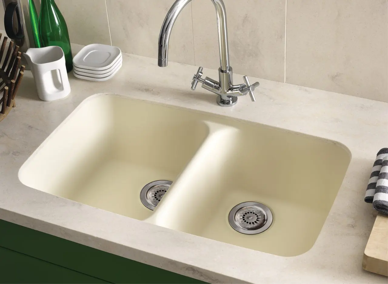 Cream-colored double kitchen sink with chrome faucet and drain stoppers.