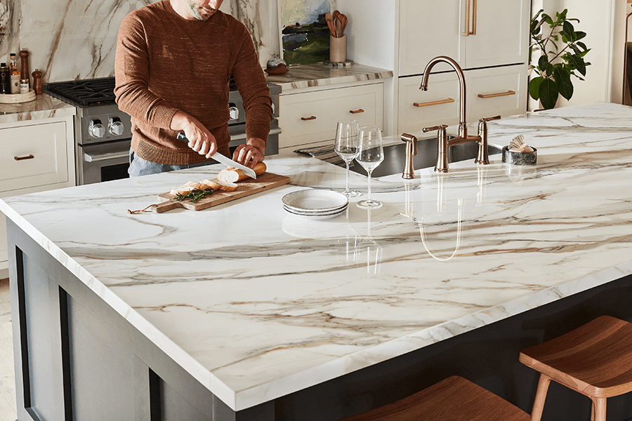 Man slicing bread on a marble kitchen island counter.