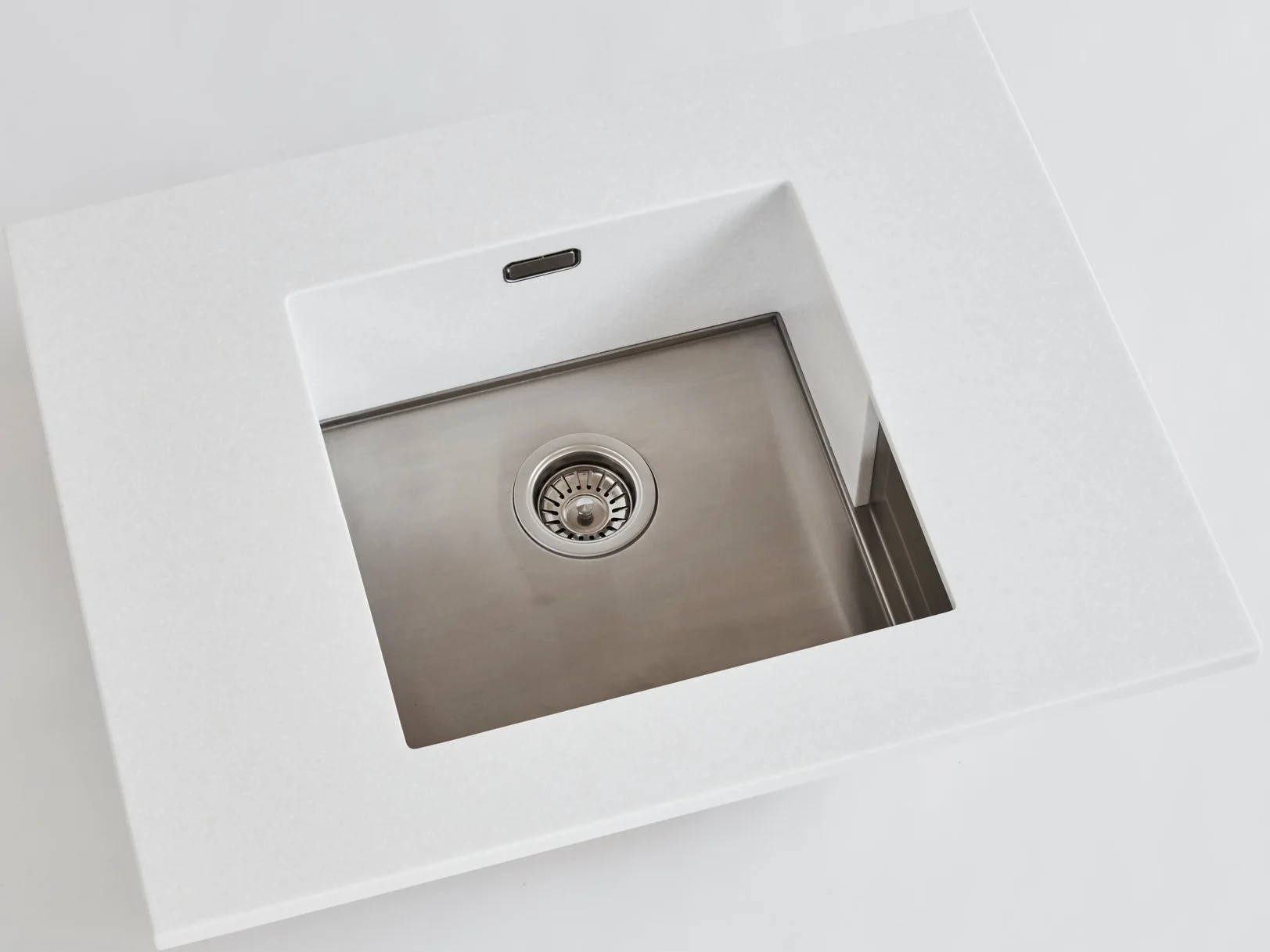 Modern stainless steel kitchen sink with white countertop.